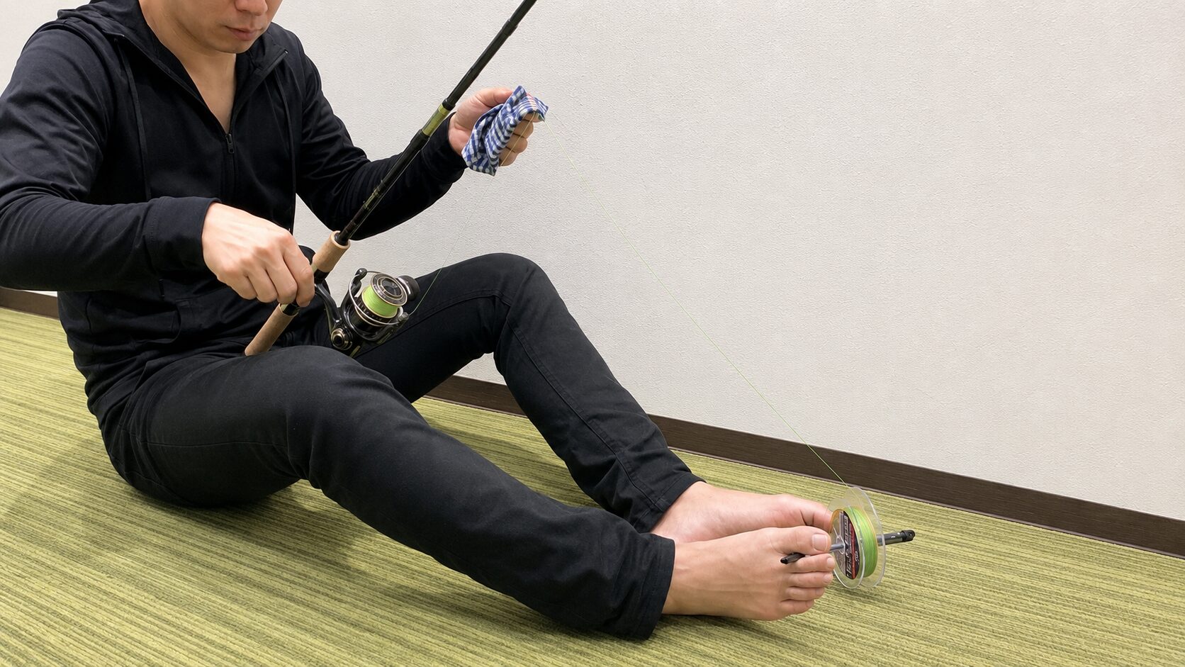ラインを指と濡れタオルで押さえてテンションを掛けて巻く手元